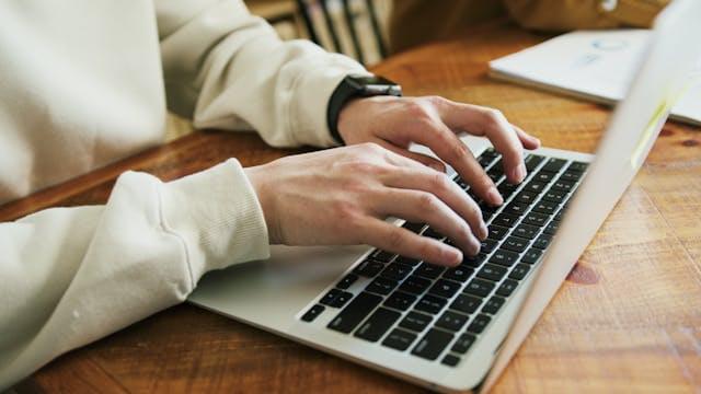 Ręce piszą zapytanie na laptopie